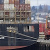 A cargo container mover carries a container at right next to a cargo ship operated by Yang Ming Marine Transport Corp. at the Port of Tacoma, Friday, Feb. 20, 2015, in Tacoma, Wash.