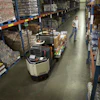 A warehouse worker uses Crown's QuickPick Remote to move the lift truck ahead in the aisle, eliminating the need to step up and down off the truck to move to the next pick position.