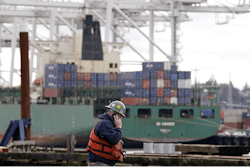 A worker walks near a container ship being loaded at the Port of Seattle, Monday, Feb. 9, 2015, in Seattle.