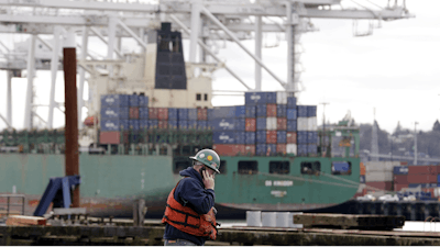 A worker walks near a container ship being loaded at the Port of Seattle, Monday, Feb. 9, 2015, in Seattle.