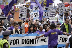 Protesters, including college students, fast-food restaurant employees and other workers, display placards as they march Tuesday, April 14, 2015, in Boston. Organizers of the event are calling for the nation's lowest paid workers to earn at least $15 per hour.