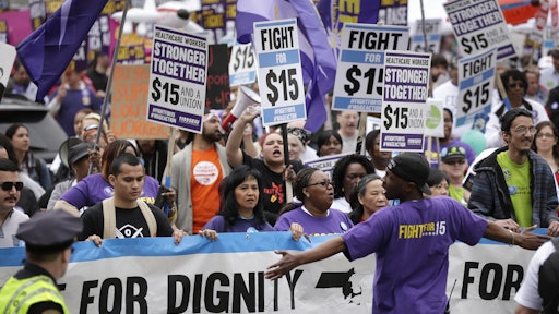 Protesters, including college students, fast-food restaurant employees and other workers, display placards as they march Tuesday, April 14, 2015, in Boston. Organizers of the event are calling for the nation's lowest paid workers to earn at least $15 per hour.