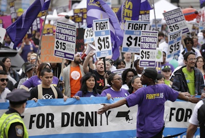 Protesters, including college students, fast-food restaurant employees and other workers, display placards as they march Tuesday, April 14, 2015, in Boston. Organizers of the event are calling for the nation's lowest paid workers to earn at least $15 per hour.