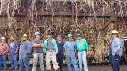 Some of the remaining workers at the mill stand in front of the last hauler truck of Hawaiian sugar cane.