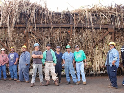 Some of the remaining workers at the mill stand in front of the last hauler truck of Hawaiian sugar cane.