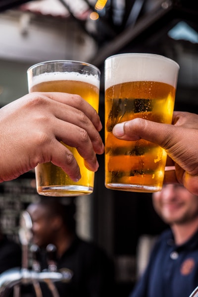 Two Persons Holding Drinking Glasses Filled With Beer 1089930
