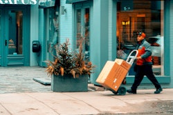 Man Pushing Hand Truck Beside Building 2047397
