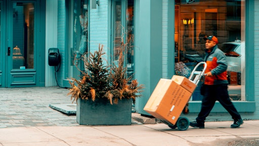 Man Pushing Hand Truck Beside Building 2047397