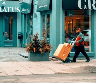 Man Pushing Hand Truck Beside Building 2047397