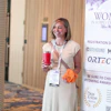 Smiling woman at Women in Supply Chain Forum conference holding red drink