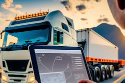Fleet management tablet displaying route tracking with commercial trucks on highway at sunset