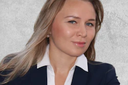 Professional headshot of a woman in navy blazer and white blouse against gray textured background
