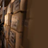 Person in dark winter gear examining cardboard boxes in warehouse storage facility