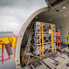 DHL cargo container being loaded into aircraft by workers in safety vests at airport terminal