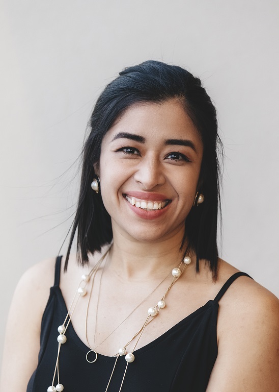 Professional headshot of smiling woman with dark hair wearing black top and pearl necklace Headshot