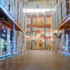 Modern warehouse interior with digital overlay showing storage shelves, green efficiency indicators, and networked connectivity icons