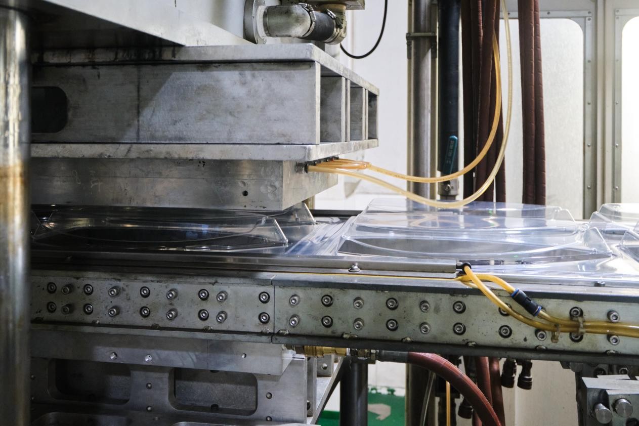 Industrial CNC machine or 3D printer with metal frame, control panel buttons, and yellow wiring in workshop setting