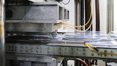 Industrial CNC machine or 3D printer with metal frame, control panel buttons, and yellow wiring in workshop setting