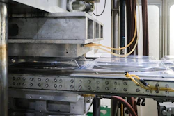 Industrial CNC machine or 3D printer with metal frame, control panel buttons, and yellow wiring in workshop setting