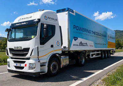 White IVECO refrigerated truck branded with NIVALIS cold chain logistics company branding, parked on a rural road with green landscape and blue sky.
