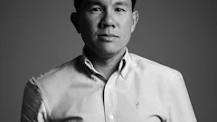 Professional black and white portrait of an Asian man wearing a light-colored button-up shirt against a neutral gray background