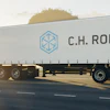 C.H. Robinson refrigerated truck traveling on highway at sunset with trees in background