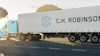 C.H. Robinson refrigerated truck traveling on highway at sunset with trees in background