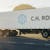 C.H. Robinson refrigerated truck trailer driving on highway at sunset with trees in background