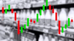 Candlestick chart with red and green bars showing financial market price movements overlaid on industrial warehouse background