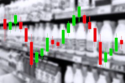 Candlestick chart with red and green bars showing financial market price movements overlaid on industrial warehouse background