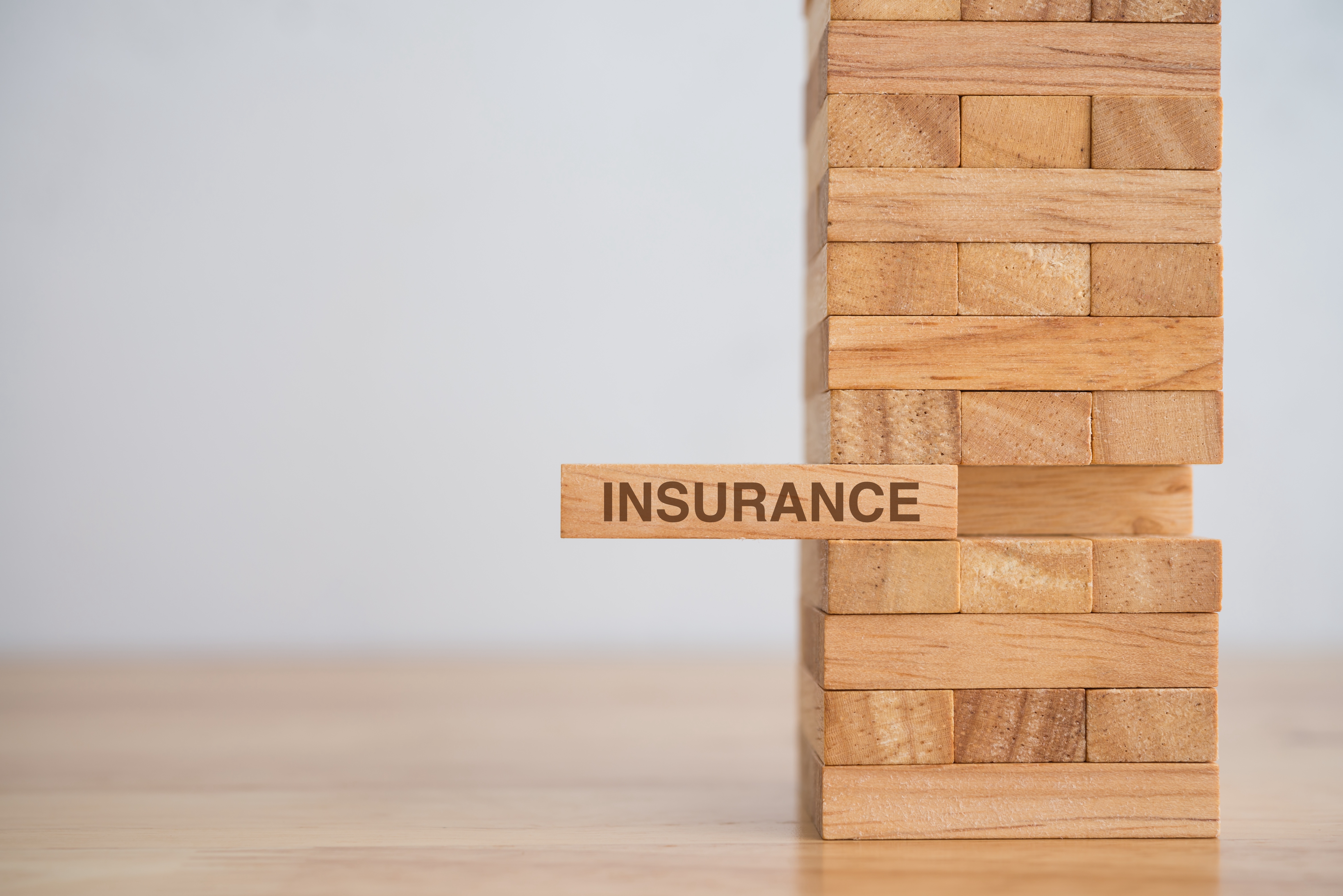 Wooden block tower with 'Insurance' text block representing financial stability and risk management