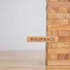 Wooden block tower with 'Insurance' text block representing financial stability and risk management