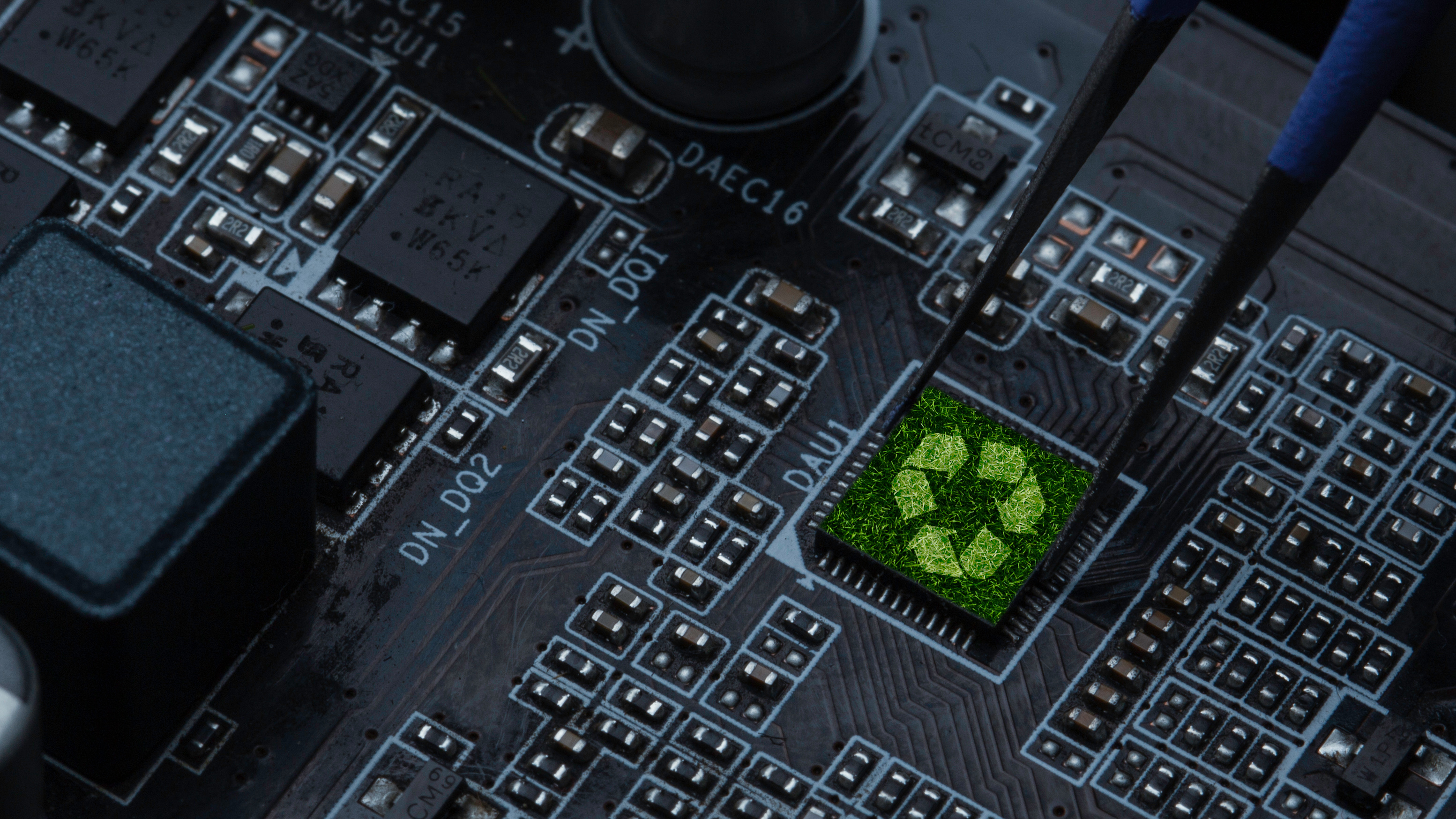 Green recycling symbol on computer circuit board with electronic components