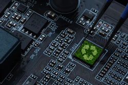 Green recycling symbol on computer circuit board with electronic components